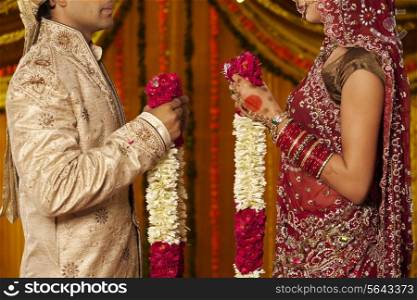 Indian bride and groom holding garlands
