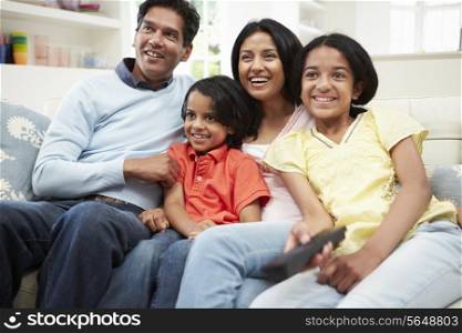 Indian Family Sitting On Sofa Watching TV Together