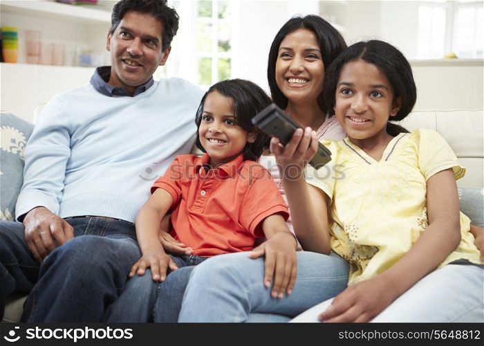 Indian Family Sitting On Sofa Watching TV Together