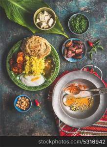 Indian food meals in bowls served with banana leaf: Curry, butter chicken, rice, lentils, paneer, samosa, naan, chutney, spices. Traditional south indian cuisine.