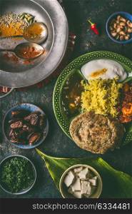 Indian food, various dinner meals in bowls on dark rustic background, top view