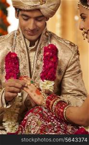 Indian groom putting a wedding ring on a bride
