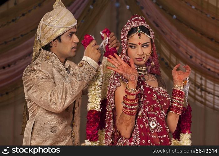 Indian groom trying to put a garland on his bride