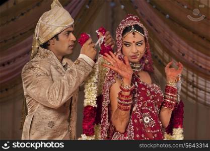 Indian groom trying to put a garland on his bride