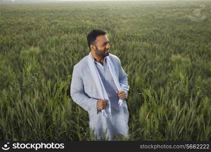 Indian man looking away while standing in a field