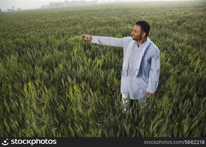 Indian man pointing at something while standing in a field