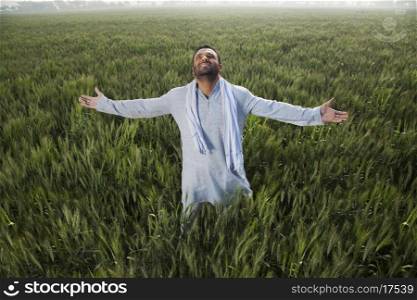Indian man standing in field with arms out
