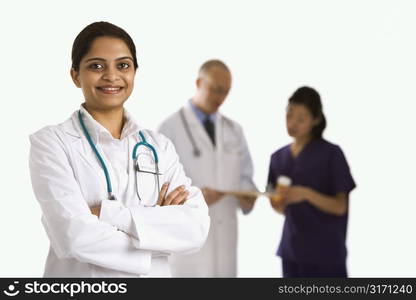 Indian mid adult woman doctor standing with medical staff in background.