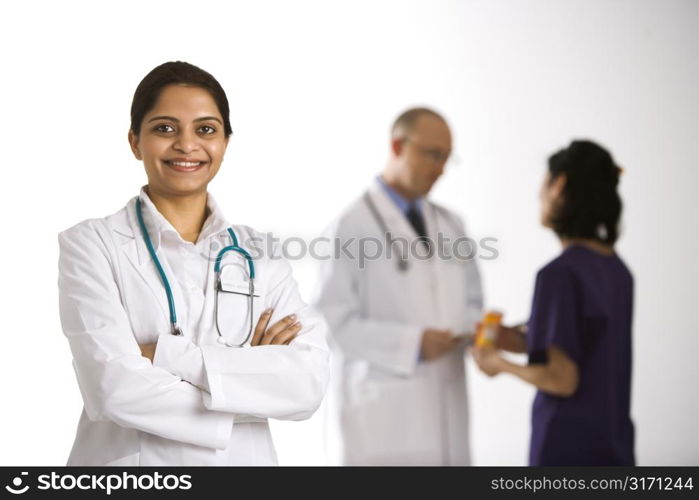 Indian mid adult woman doctor standing with medical staff in background.