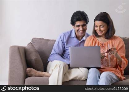 Indian middle age couple shopping online through laptop using credit card