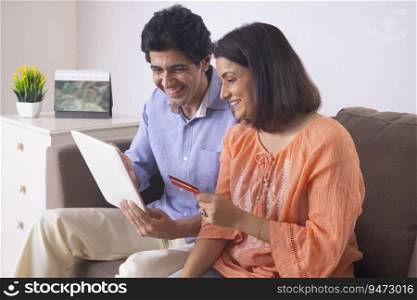 Indian middle age couple shopping online through tablet using credit card