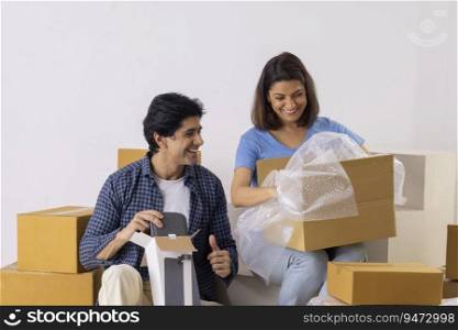 Indian middle age couple unpacking cardboard boxes in new room
