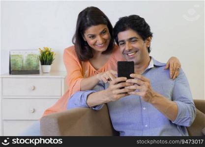 Indian middle age couple watching smartphone at home