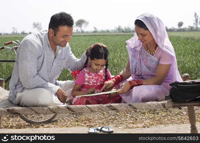 Indian mother and father helping daughter with her homework