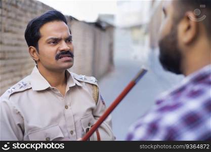 Indian policeman threatening someone by raising baton