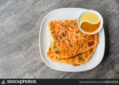 Indian Roti Prata with Condensed milk and Curry Sauce, close up of rustic Indian Roti fried pancake