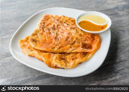 Indian Roti Prata with Condensed milk and Curry Sauce, close up of rustic Indian Roti fried pancake