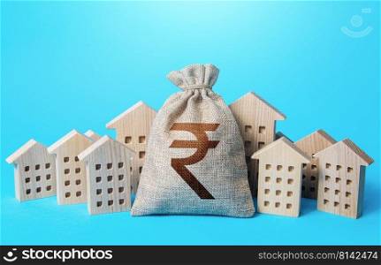 Indian rupee money bag among town houses figurines. Realtor services. Sale of real estate. property taxes. Tax collection, investment in city development. Municipal budgeting. Rental business.