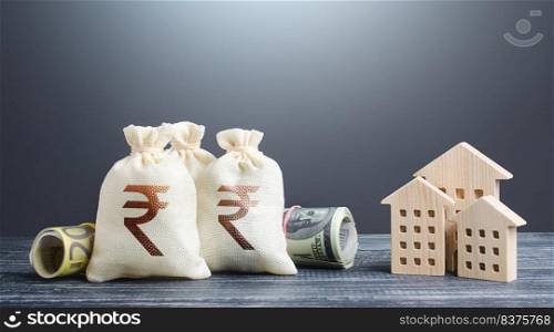 Indian rupee money bags and residential buildings figures. Investments in real estate. Mortgage loan. Financing the construction and renovation of housing. Municipal budget management. Taxes.