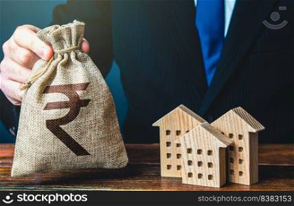 Indian rupee money bags and residential buildings figures. Taxes. Bank offer of mortgage loan. Rental business. Sale of housing. Buy. Municipal budget. Real estate investments, construction industry.