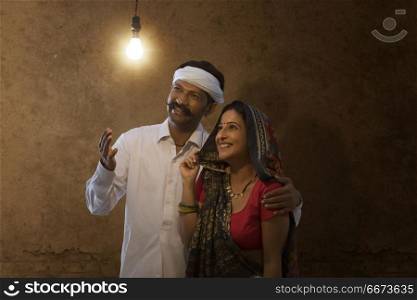 Indian rural couple looking at light bulb