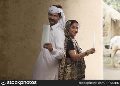 Indian Rural couple standing back to back showing bank cheque