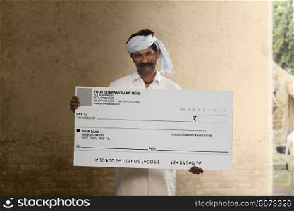 Indian rural man showing a bank cheque