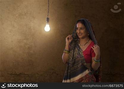 Indian rural woman looking at light bulb in house