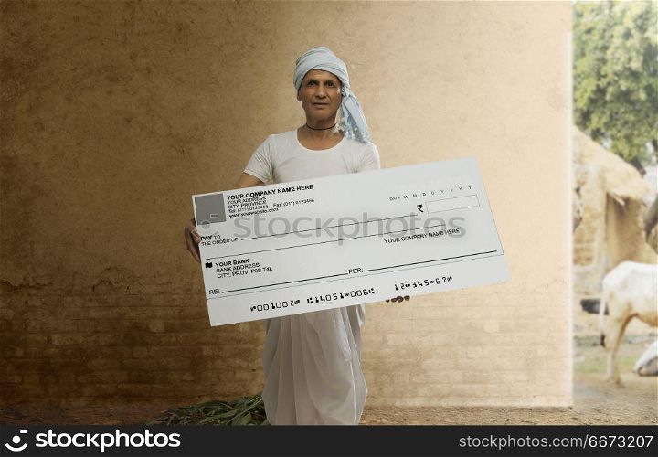 Indian senior farmer showing a bank cheque