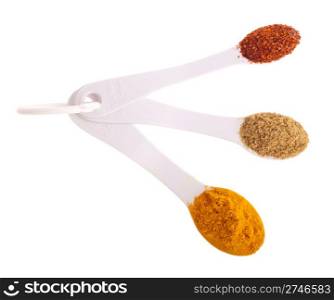 indian spices in measuring spoons (curcuma, coriander, red pepper flakes) isolated on white background