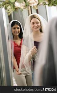 Indian woman and Caucasian woman trying on veils and looking in mirror.