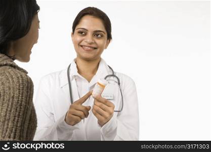 Indian woman doctor explaining medication to Asian woman patient.
