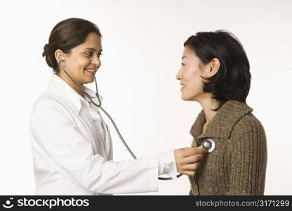 Indian woman doctor using stethescope on Asian woman patient.