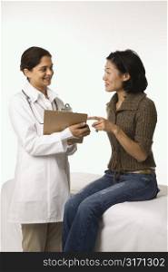 Indian woman doctor with Asian woman patient.