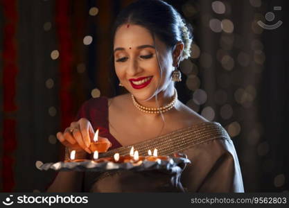 Indian woman keeping a diya in the plate on the occasion of Diwali