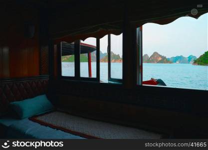 Indochina junk cruise to Halong Bay, Vietnam, Southeast Asia. Panoramic window in cabin. View from room window. Sea tour at Ha Long Bay. Most popular, famous landmark, tourist destination of Vietnam