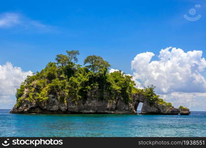 Indonesia. A small rocky tropical island in the background of the ocean and beautiful clouds. Rocky Tropic Islet in Indonesia