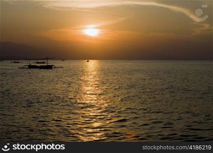 Indonesia. Bali. A sunset over ocean and a boat silhouette.