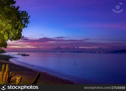 Indonesia. Coast of the bay between the islands after sunset. Boats and lights of the other shore. Summer Bay After Sunset