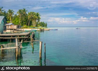 Indonesia. Several buildings and boats on the shore of a tropical island. The vast ocean to the horizon. Coastal Village on a Tropical Island