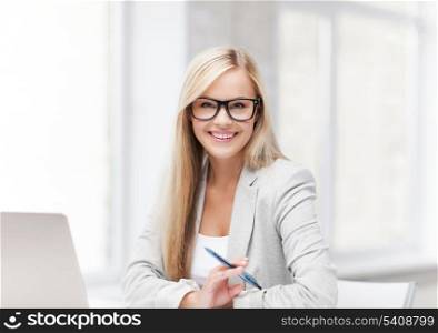 indoor picture of smiling woman with laptop and pen