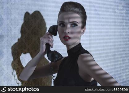 indoor shoot of fashion elegant woman talking on vintage phone with worried expression, indoor half-light atmosphere