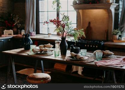 Indoor shot of served table with rolled napkins. Dinner time concept. Table setting decor. Interior of home kitchen. Rustic serving