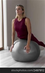 indoors mature woman using silver fitness ball