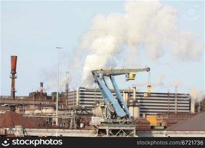 Industrial area with heavy equipment and smoking chimney