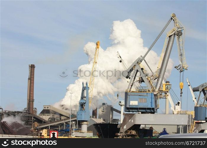 Industrial area with heavy equipment and smoking chimney