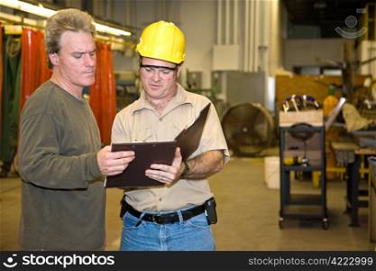 Industrial auditor discussing his inspection results with the factory owner.