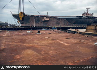 Industrial background of rusty metal platform in the dock port with battleship