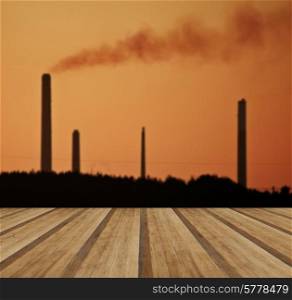 Industrial chimney stacks polluting the air in a natural landscape setting with wooden planks floor