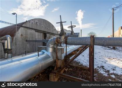 industrial concept - outdoor pipeline and old hangar in winter. outdoor pipeline and old hangar in winter